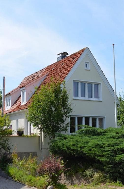 Das weiße Ferienhaus mit rotem Ziegeldach hinter einer grünen Hecke