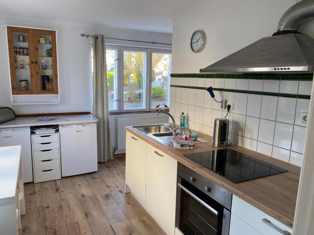 Küche mit weißen Fronten, Holzarbeitsplatte, Induktionskochfeld und Dunstabzugshaube