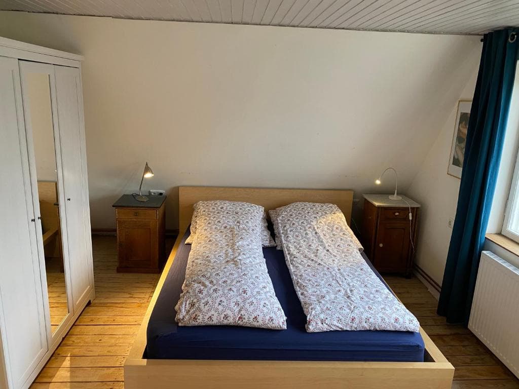 Schlafzimmer mit Doppelbett, Kleiderschrank und zwei Nachttischen mit Leselampen