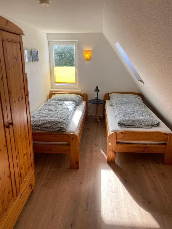 Zimmer mit zwei Einzelbetten aus Kiefernholz und passendem Kleiderschrank