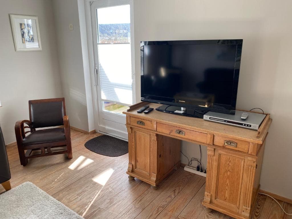 Alter Holzschreibtisch mit Flachbild-Fernseher und Ledersessel am Fenster