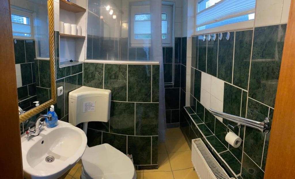Duschbad mit dunkelgrünen Fliesen, Waschbecken, WC und Dusche