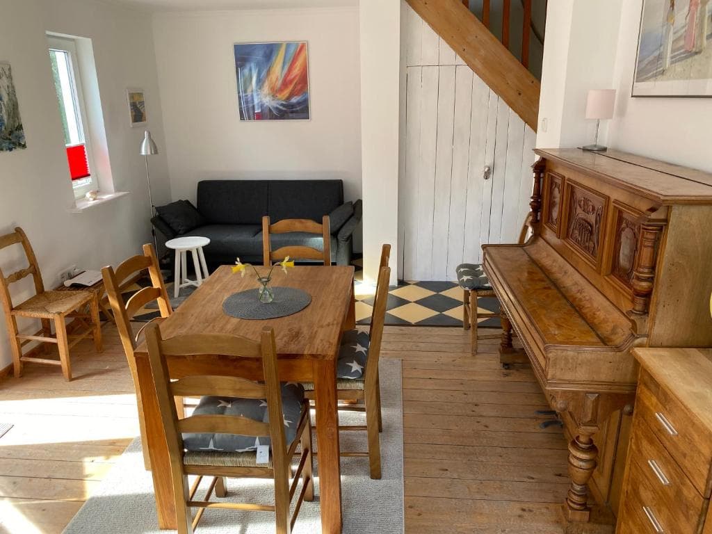 Wohnbereich mit Esstisch, Sofa und einem Klavier neben der Treppe