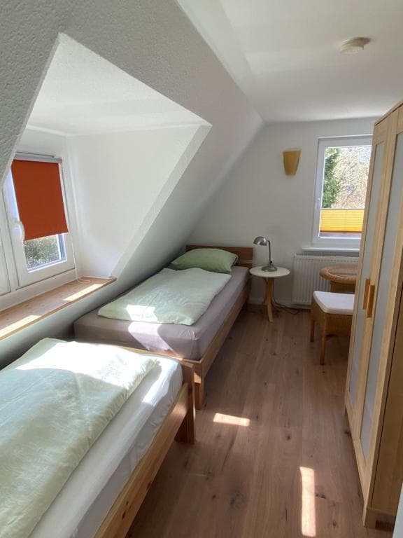 Einzelbett unter der Dachschräge neben Fenster und Kleiderschrank