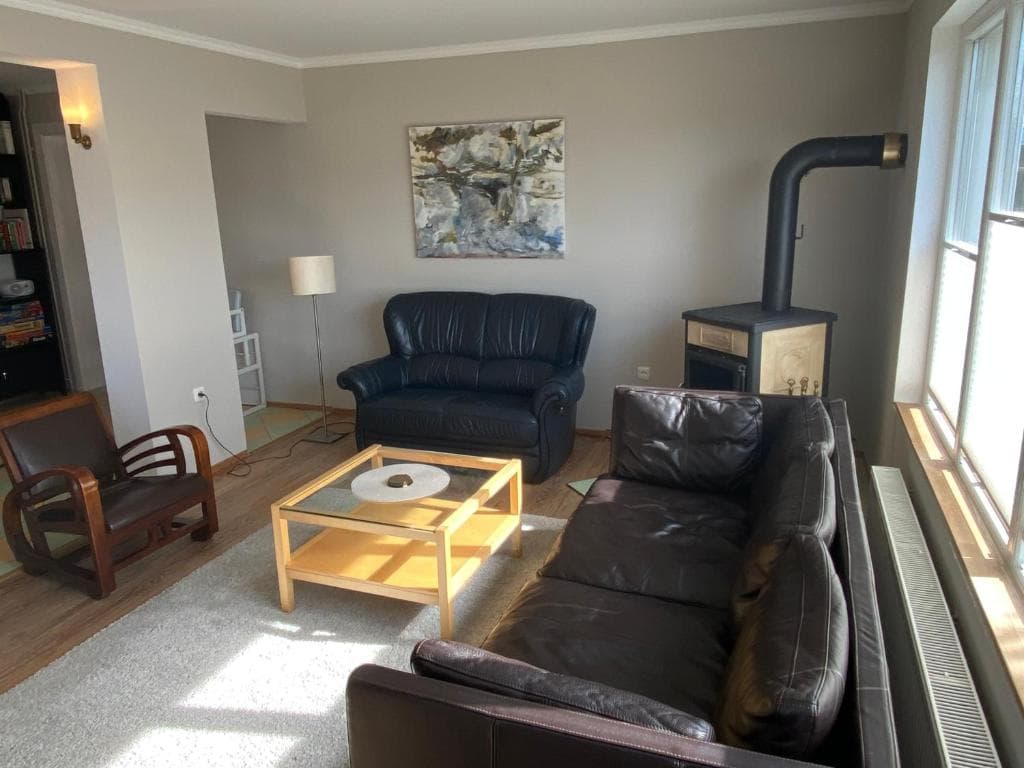 Wohnzimmer mit dunklen Ledersofas, Couchtisch und Kaminofen