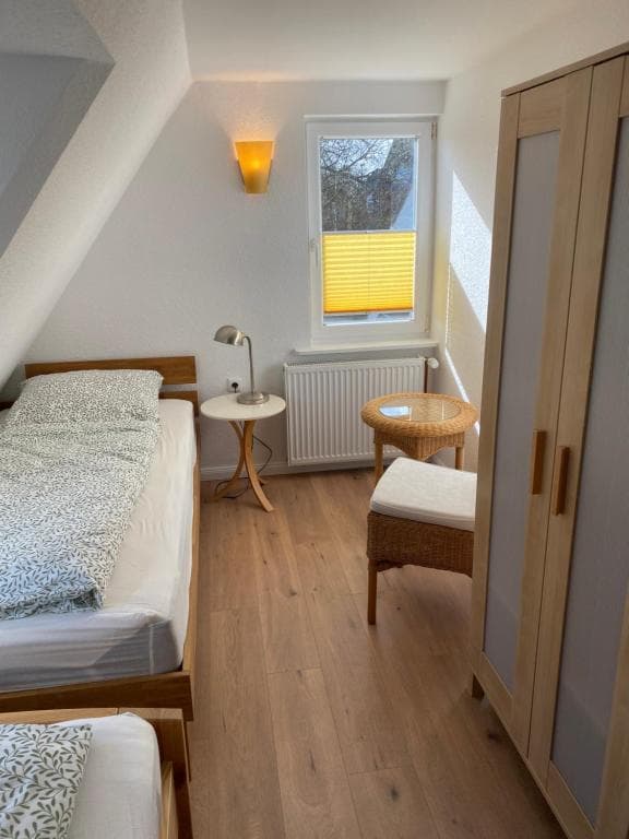 Schlafzimmer mit Einzelbett, Korbstuhl und Kleiderschrank