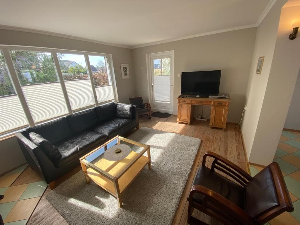Wohnzimmer mit langem Sofa vor einer breiten Fensterfront