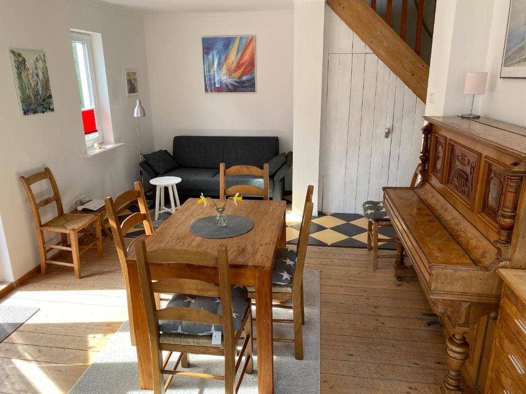 Essbereich mit Holztisch, Klavier und Blick zur hölzernen Treppe