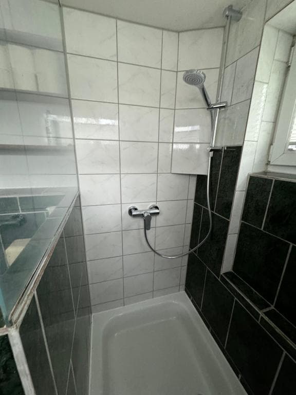 Dusche über der Badewanne mit hellen und grünen Fliesen