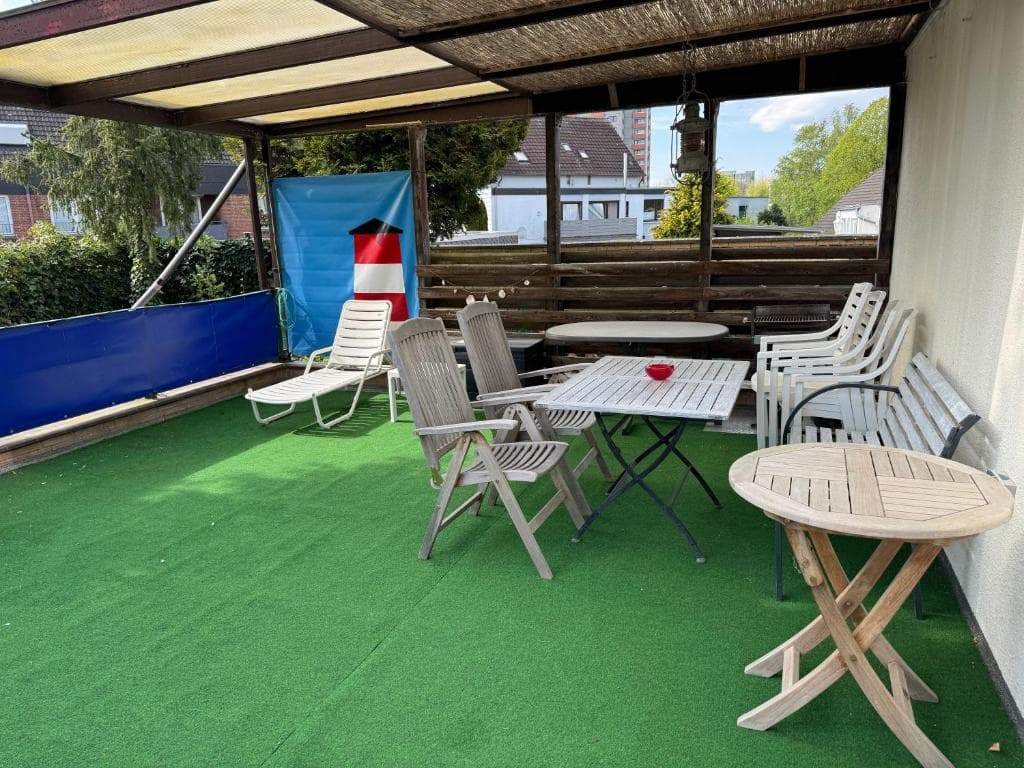 Überdachte Dachterrasse mit Liegestühlen, Gartentisch und Sichtschutz